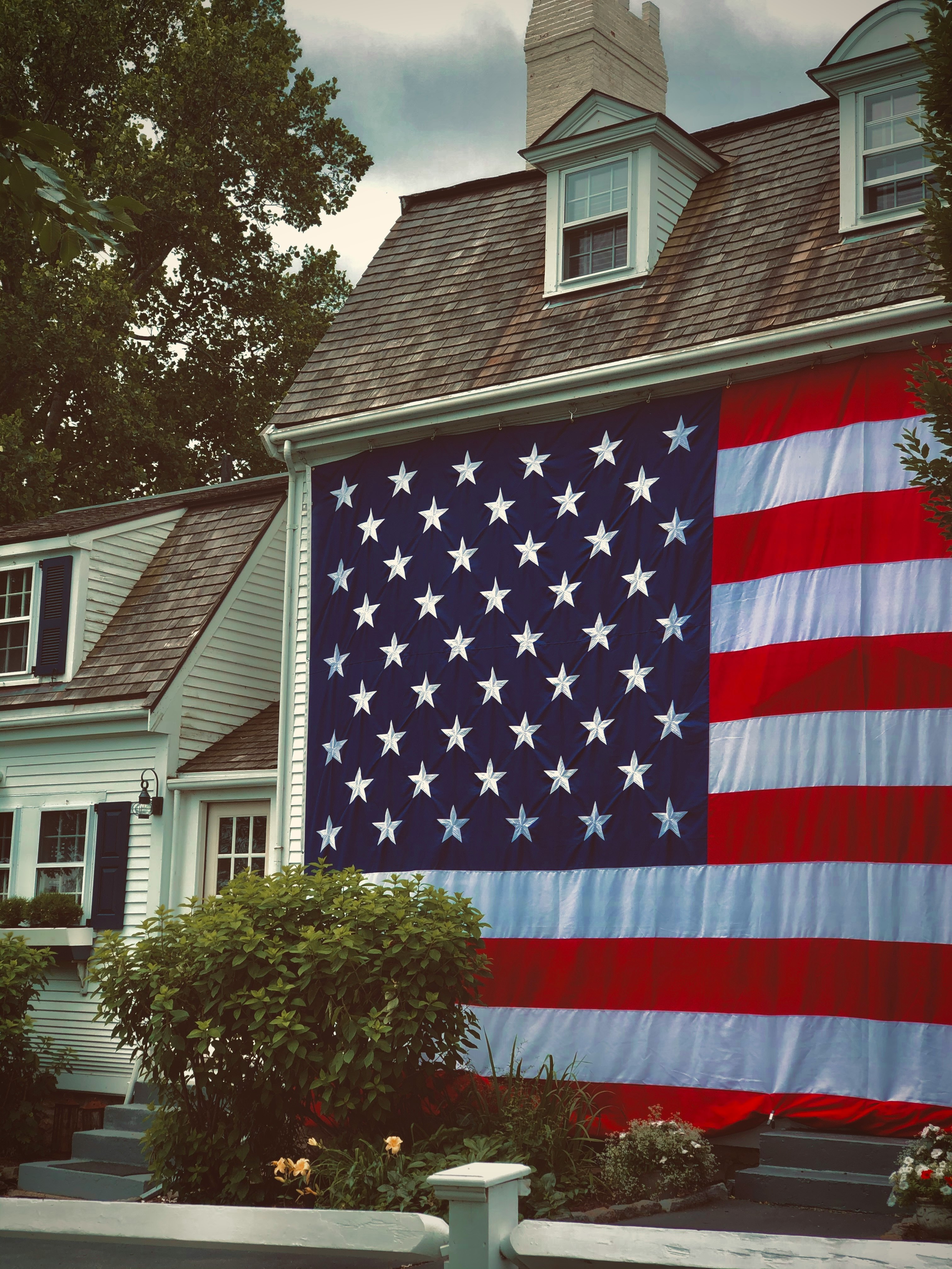 us a flag on pole near green tree during daytime